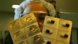 Inspeção de blísteres de medicamento por funcionário farmacêutico, um processo crucial para controlar a presença de extraíveis e lixiviáveis.