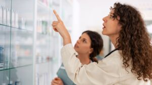 Profissionais avaliando produtos farmacêuticos em prateleira durante inspeção de controle de qualidade com suporte da Labpharma