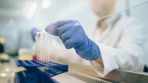 Profissional realizando análises farmacêuticas em laboratório com tubos de ensaio, controle de qualidade terceirizado pela Labpharma